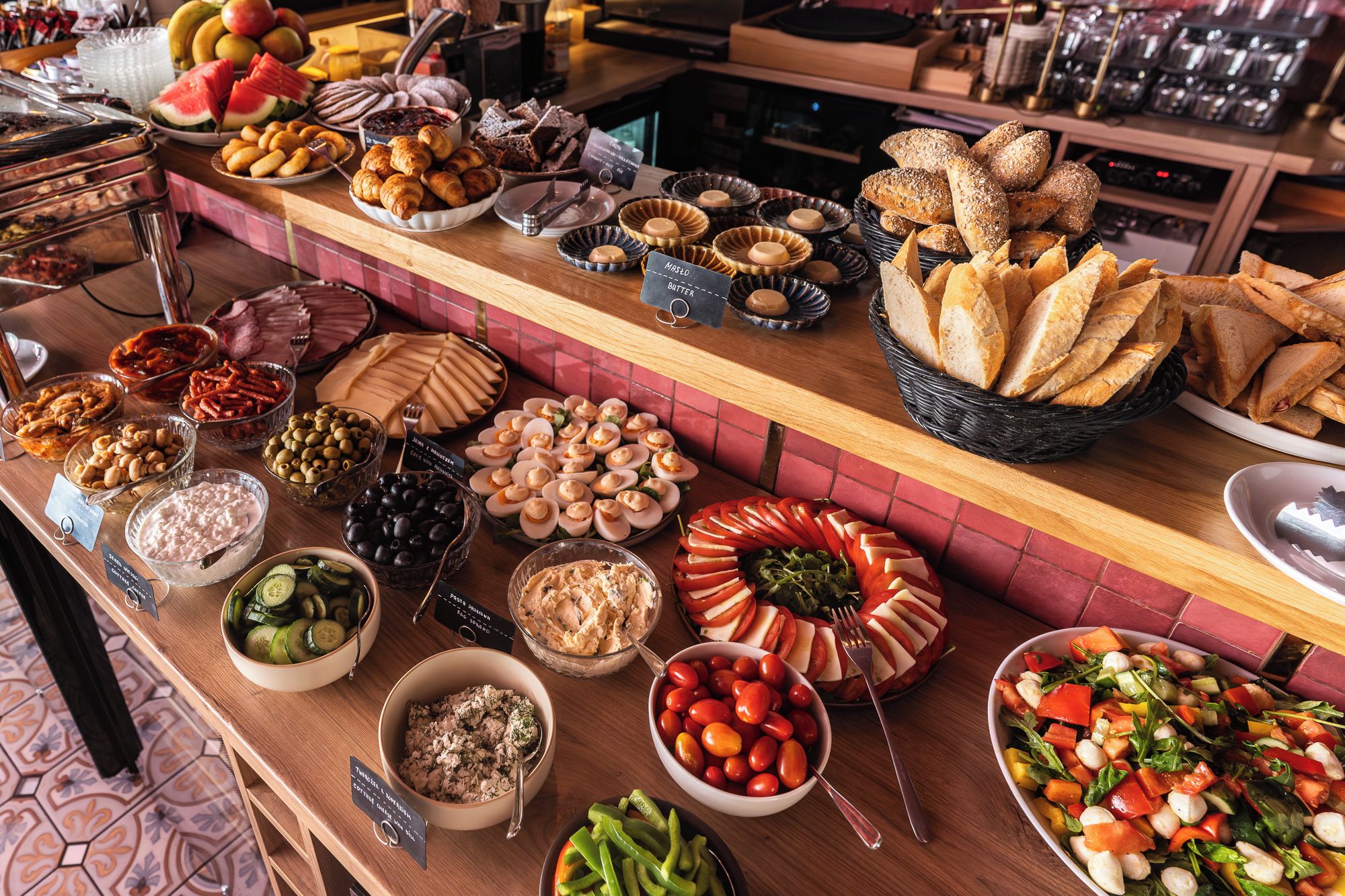 Un buffet proposant une variété d’aliments, notamment du pain, des fruits, des fromages et des salades.