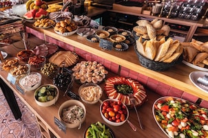 Un'ampia scelta di cibi a buffet, tra cui pane, frutta, formaggi e insalate.