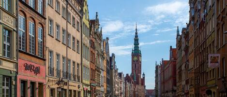 Een smalle straat met kleurrijke, historische gebouwen, een opvallende klokkentoren en een helderblauwe lucht.