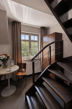 A modern room with a wooden staircase, a dining table with chairs, a vase of flowers, and a window with curtains. - Apart Neptun (Gdansk)