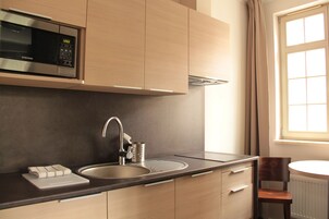 A modern kitchen with a built-in microwave, stainless steel sink, and wooden cabinets.