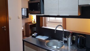 Una kitchenette compacta con microondas, un lavamanos pequeño y una cafetera.