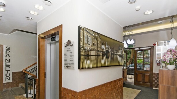 Un hall d’hôtel avec un escalier, un comptoir d’accueil et un grand tableau encadré au mur.