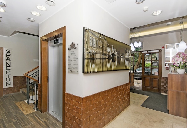 A hotel lobby with a staircase, a reception desk, and a large framed picture on the wall. - Apart Neptun (Gdansk)