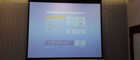Un écran de projection affiche un menu avec des options telles que « Géométrie de l’image », « Écran partagé » et « Menu ».