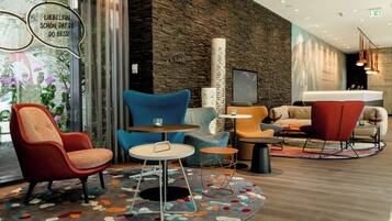 Un moderno vestíbulo de hotel con pared de piedra, asientos cómodos y una gran pantalla de televisión.