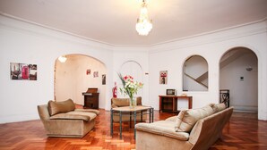 A spacious living room with two beige sofas, a round coffee table, and a chandelier. - Hotel Plaza Londres (Santiago)