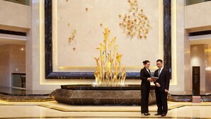 A lobby with a large decorative wall, a marble floor, and a reception desk. - Jin Jiang MingCheng Hotel (Yancheng)
