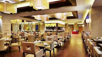 A spacious restaurant with multiple dining areas, high ceilings, and modern lighting fixtures.