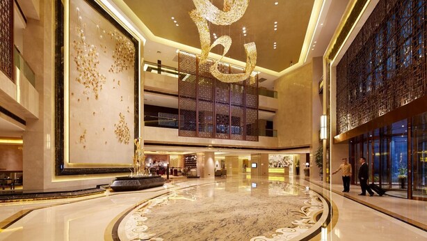 A spacious lobby with a large marble floor, a decorative ceiling sculpture, and a reception area. - Jin Jiang MingCheng Hotel (Yancheng)