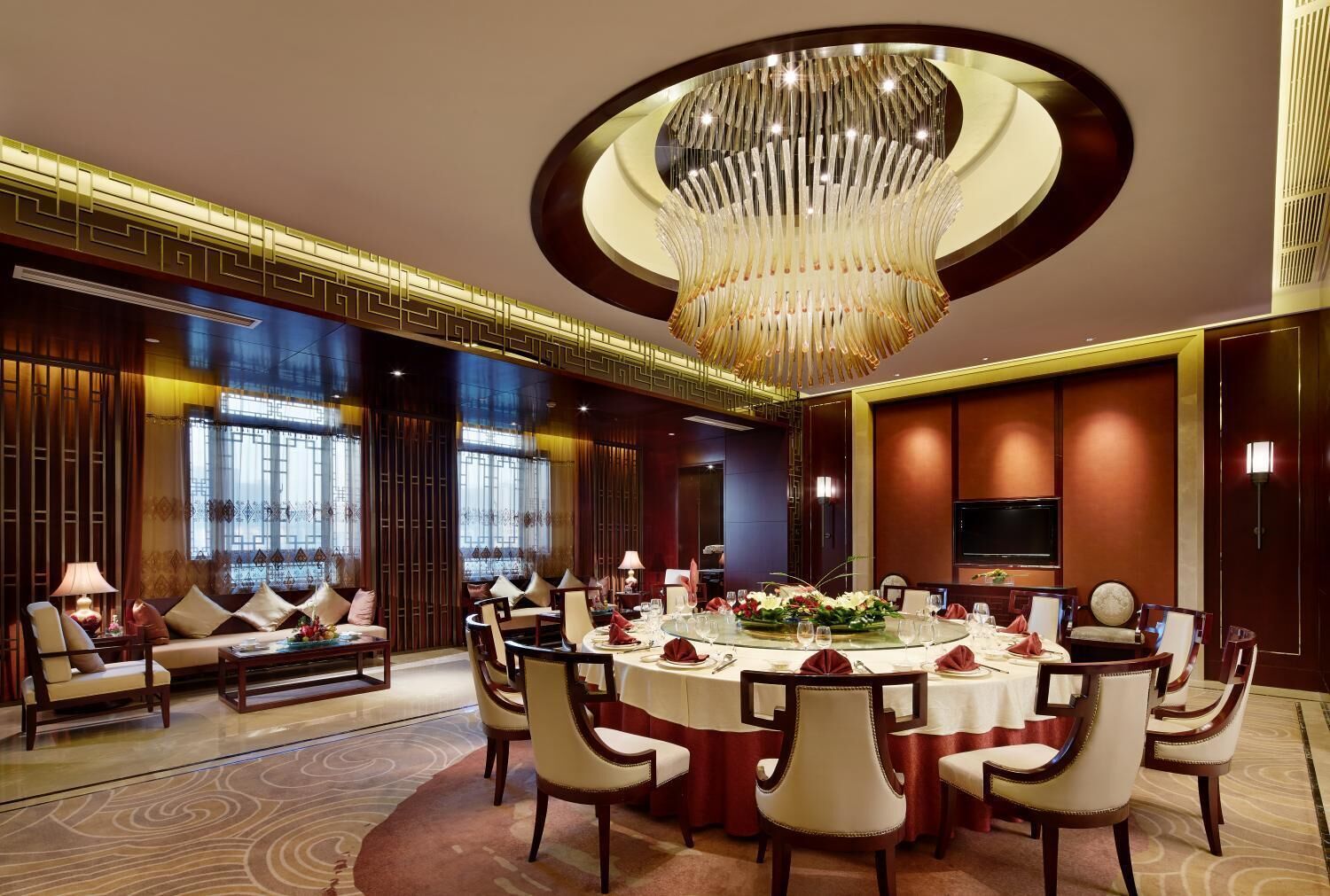 A luxurious dining room with a round table, elegant chairs, and a large chandelier.
