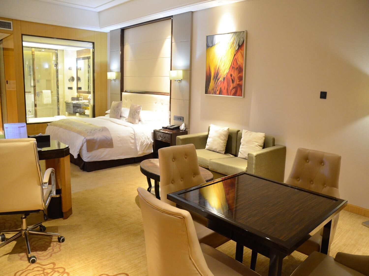 Ein Hotelzimmer mit Bett, Sofa, Esstisch und Schreibtisch.