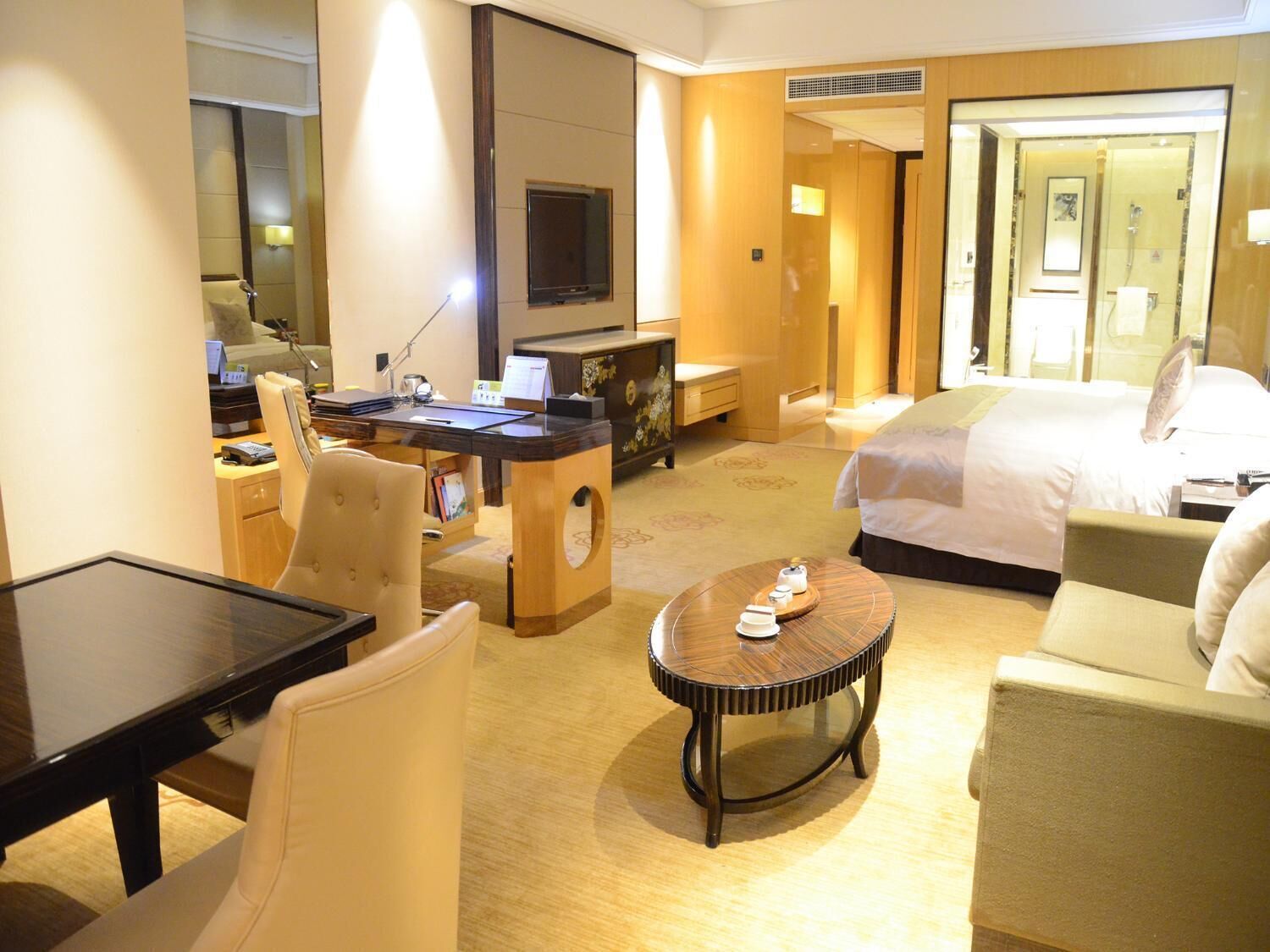 Una habitación de hotel con una cama, un escritorio, una silla, una mesa de centro y un televisor.