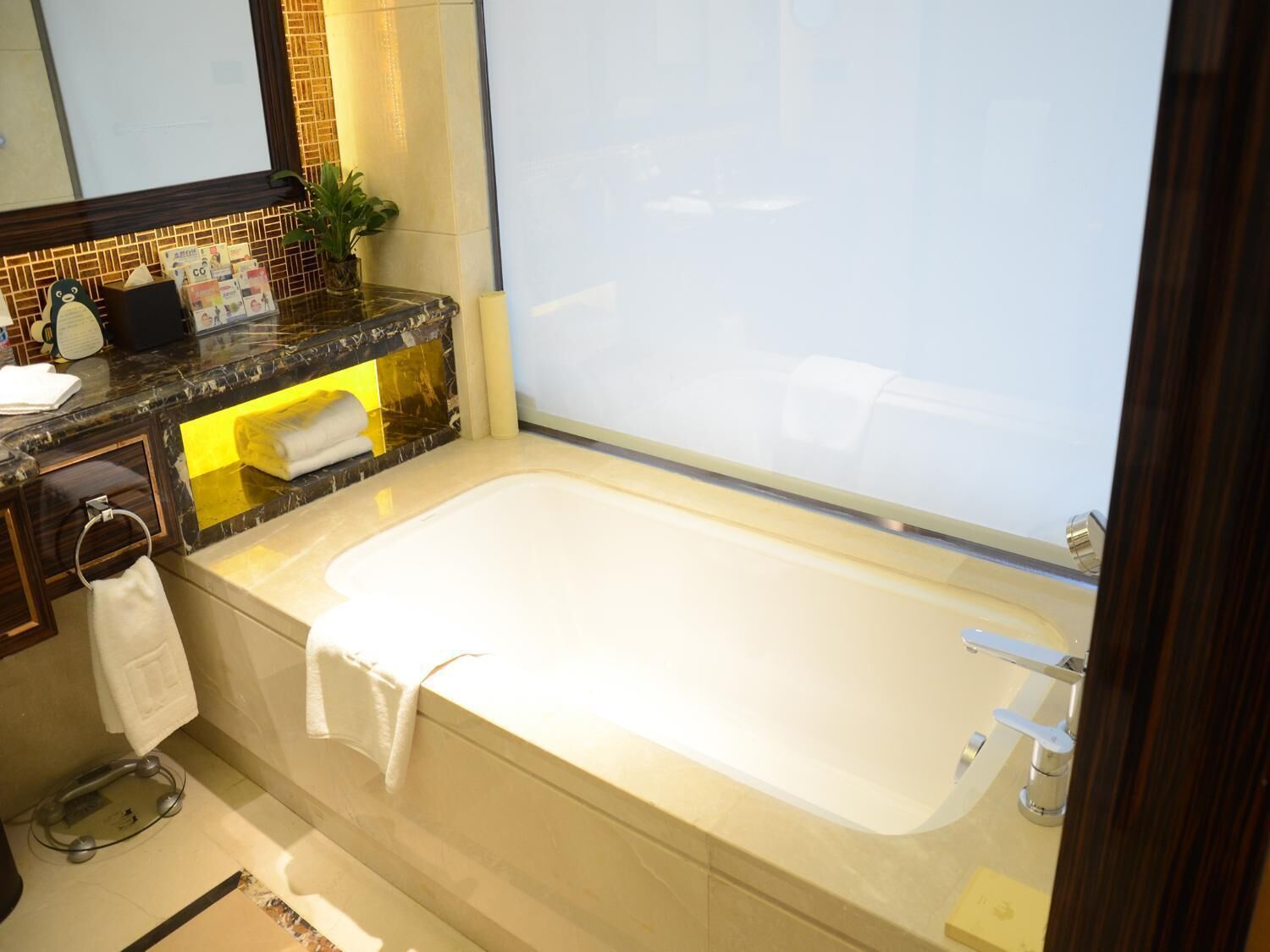 A modern bathroom with a large bathtub, a marble countertop, a sink, and a mirror.