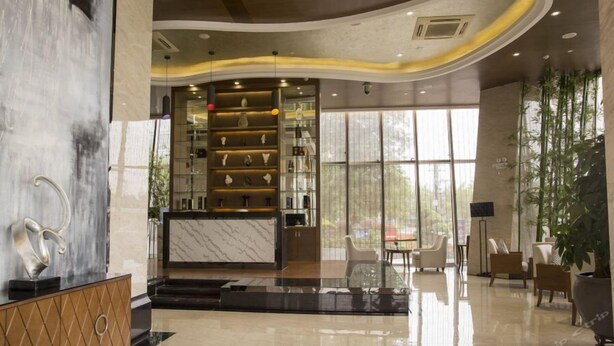 Eine moderne Lobby mit einer Marmor-Rezeption, Glastrennschränken und einer Sitzecke mit Stühlen und einem Tisch.