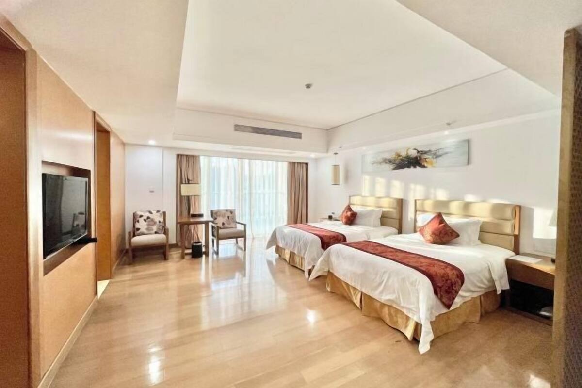 Una habitación de hotel con dos camas, televisión, escritorio y una silla.