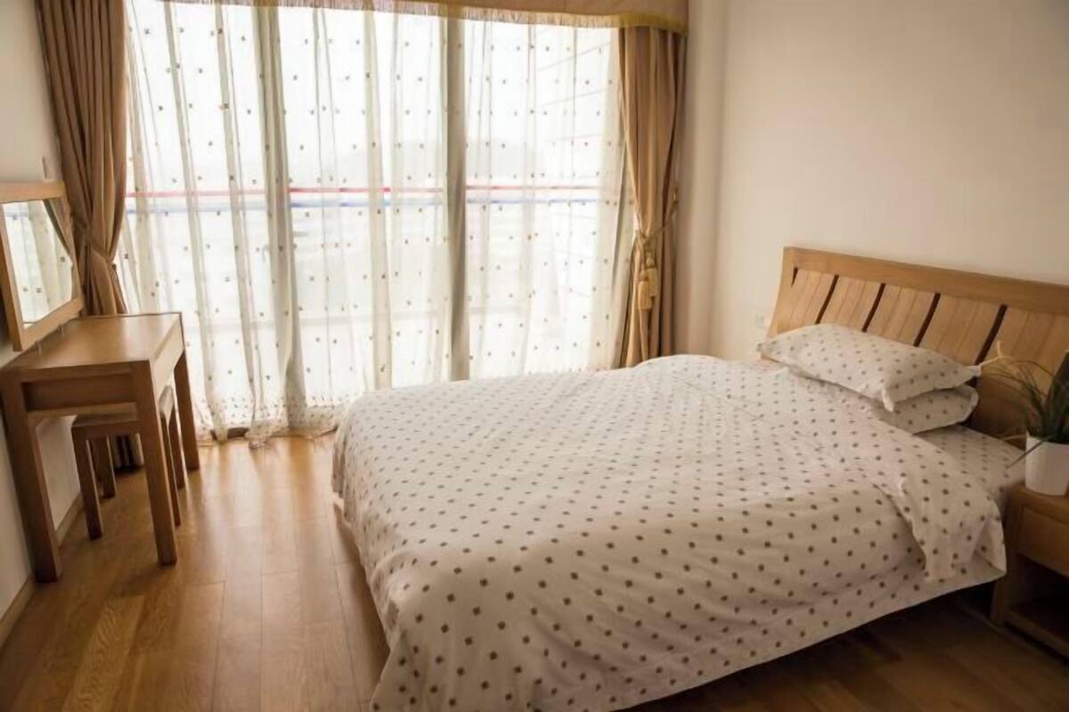 Un dormitorio con cama de madera, escritorio y ventana con cortinas.