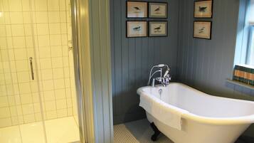 A bathroom with a white bathtub, a shower, and four framed bird pictures on the wall.