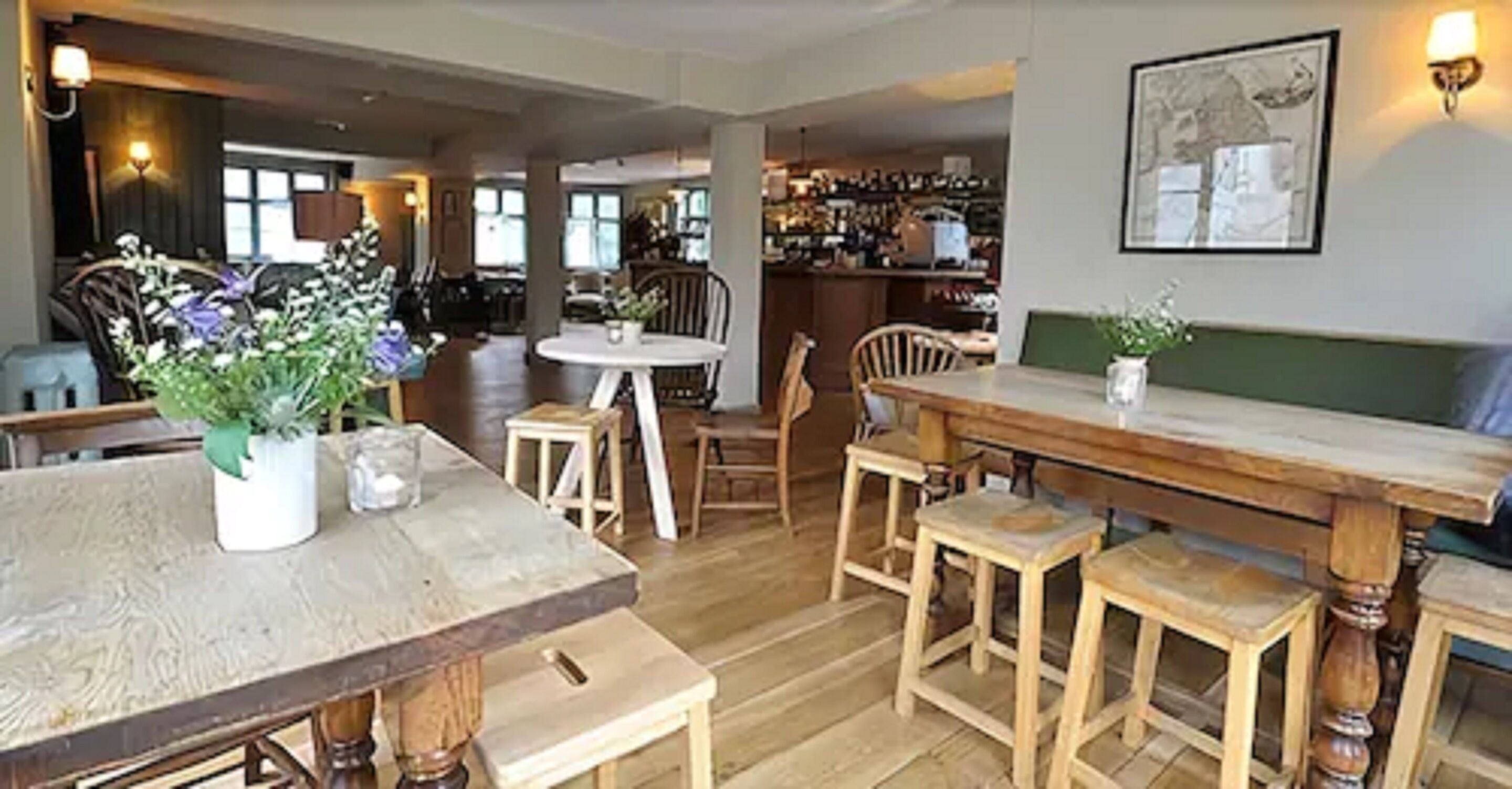 Un grand espace dédié à la salle à manger, avec des tables et des chaises en bois, un bar à l’arrière-plan et un tableau encadré au mur.