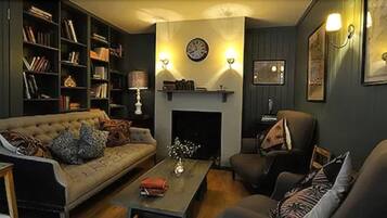 Una sala de estar acogedora con chimenea, un sofá, una mesita de centro y una estantería.