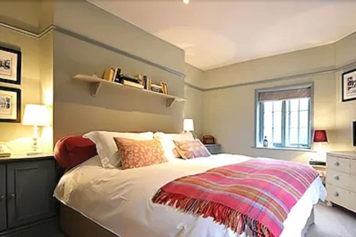 A bedroom with a bed, bedside tables, a television, and framed pictures on the wall.