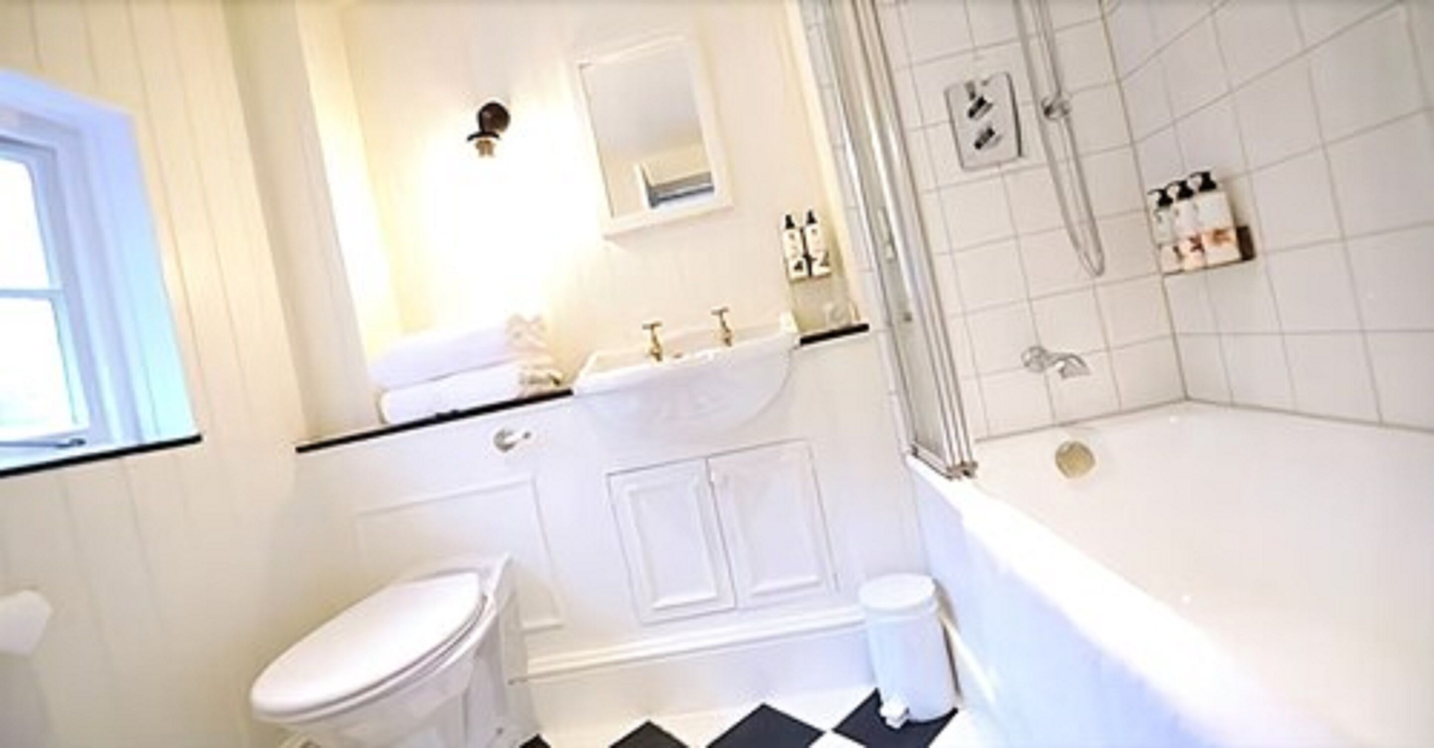 Een badkamer met toilet, wastafel, spiegel en bad.