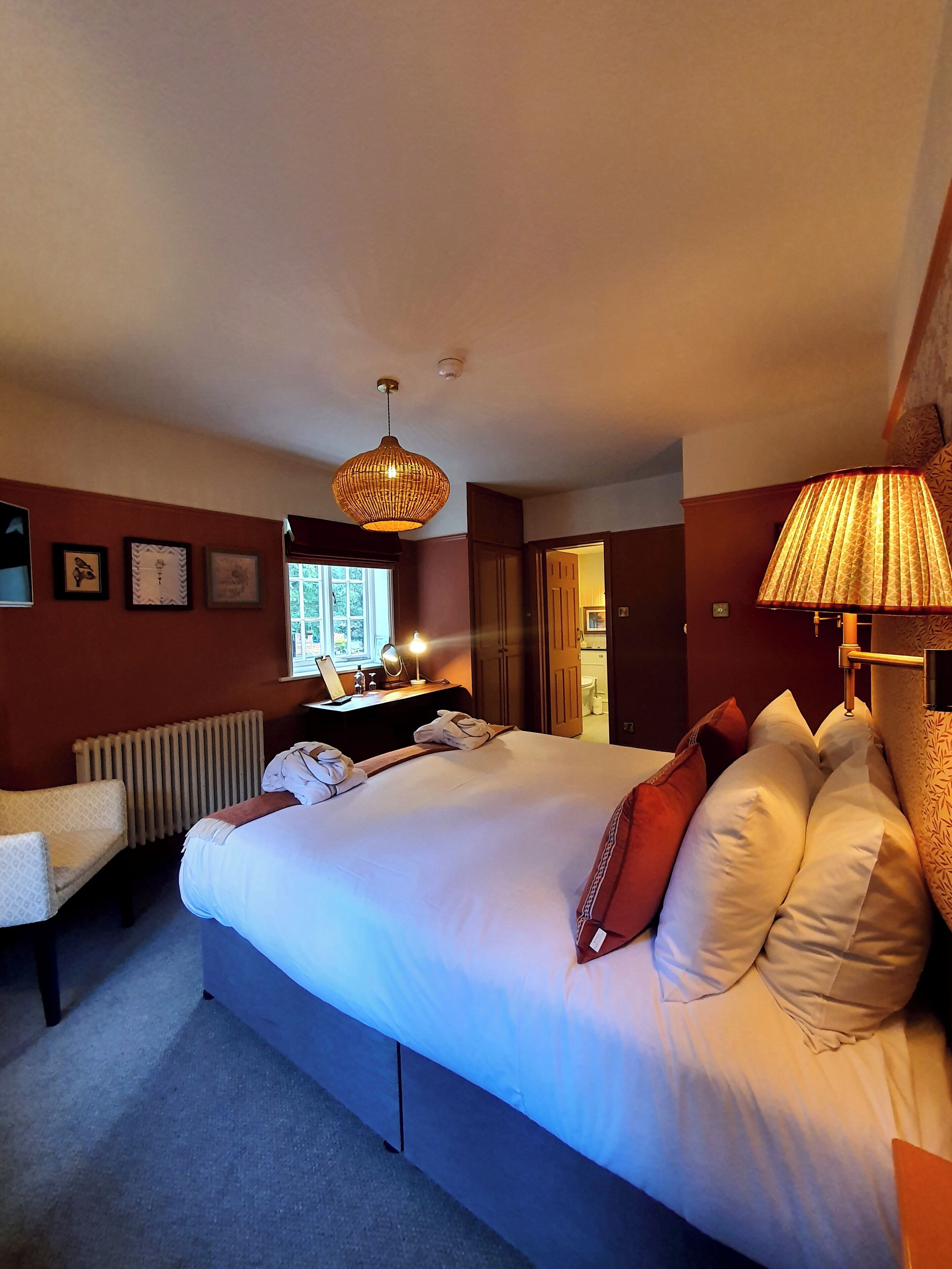 Une chambre d’hôtel avec un grand lit, un bureau avec un ordinateur, un radiateur et une fenêtre.