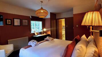 Une chambre d’hôtel avec un grand lit, un bureau avec un ordinateur, un radiateur et une fenêtre.