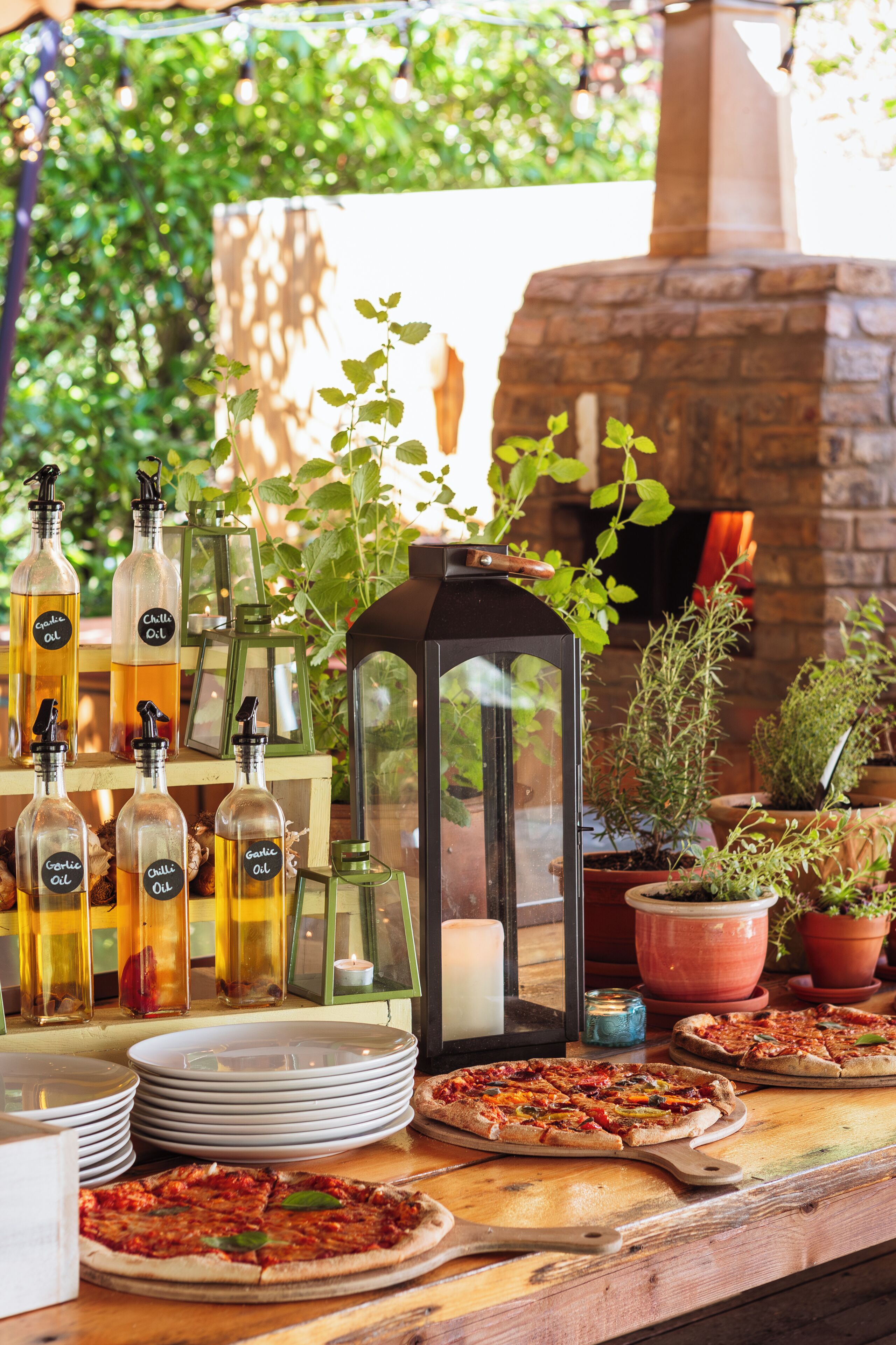 An outdoor dining area with pizza, candles, and potted plants.