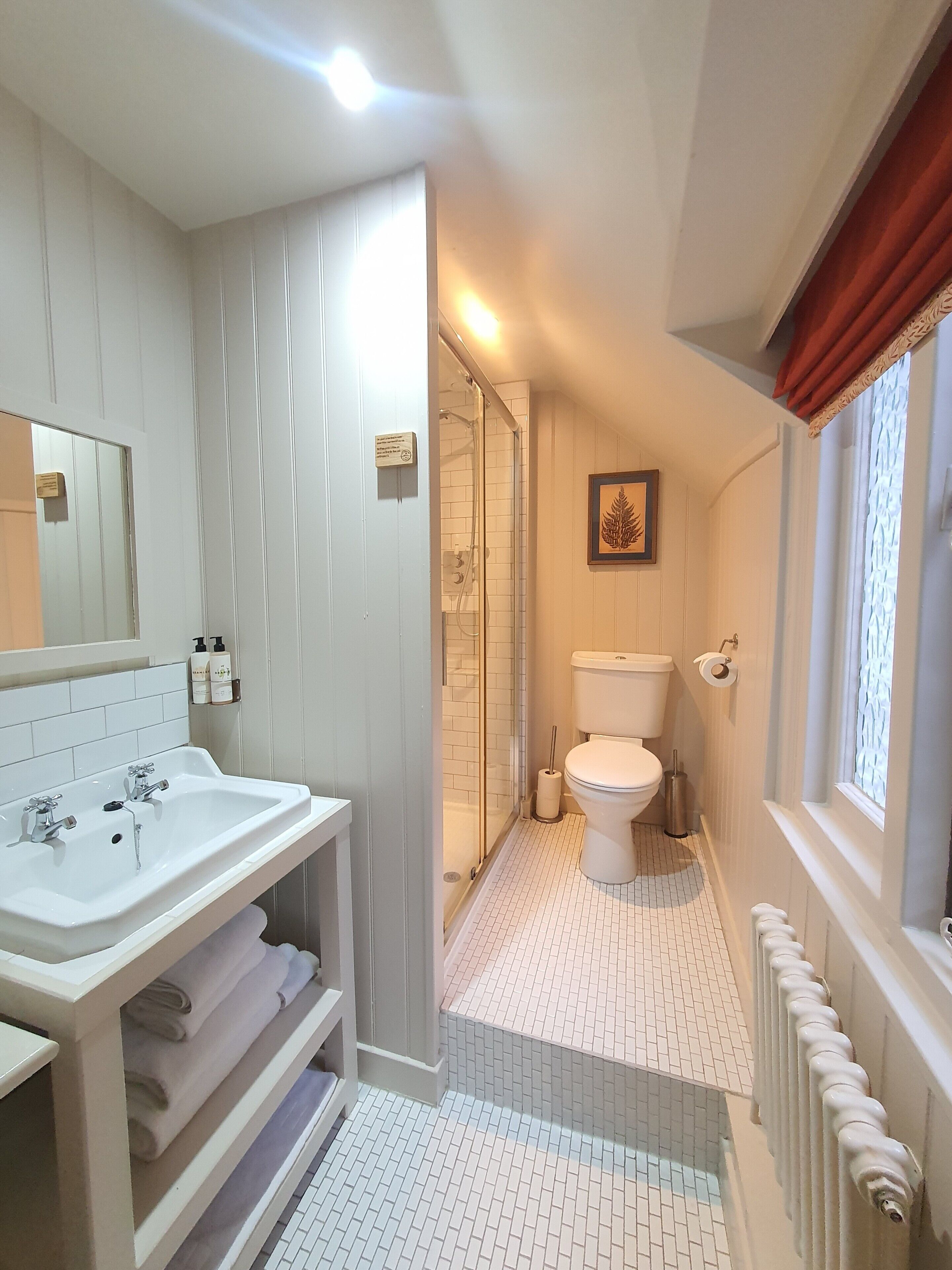A bathroom with a white sink, toilet, and shower area.