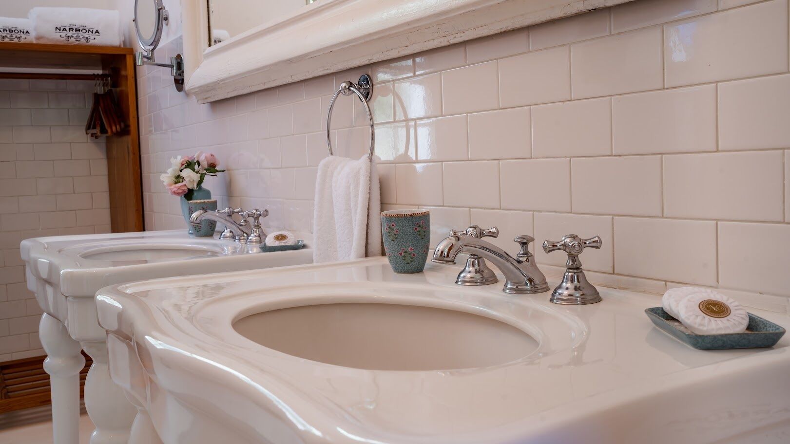 A bathroom with three sinks, a towel rack, and a mirror.