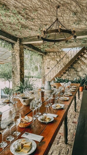 A long wooden dining table set for a meal, with wine glasses and plates, under a rustic stone ceiling with hanging vines. - Narbona Wine Lodge (Carmelo)