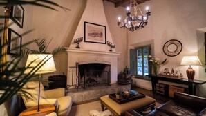 A cozy living room with a fireplace, comfortable seating, and a chandelier. - Narbona Wine Lodge (Carmelo)