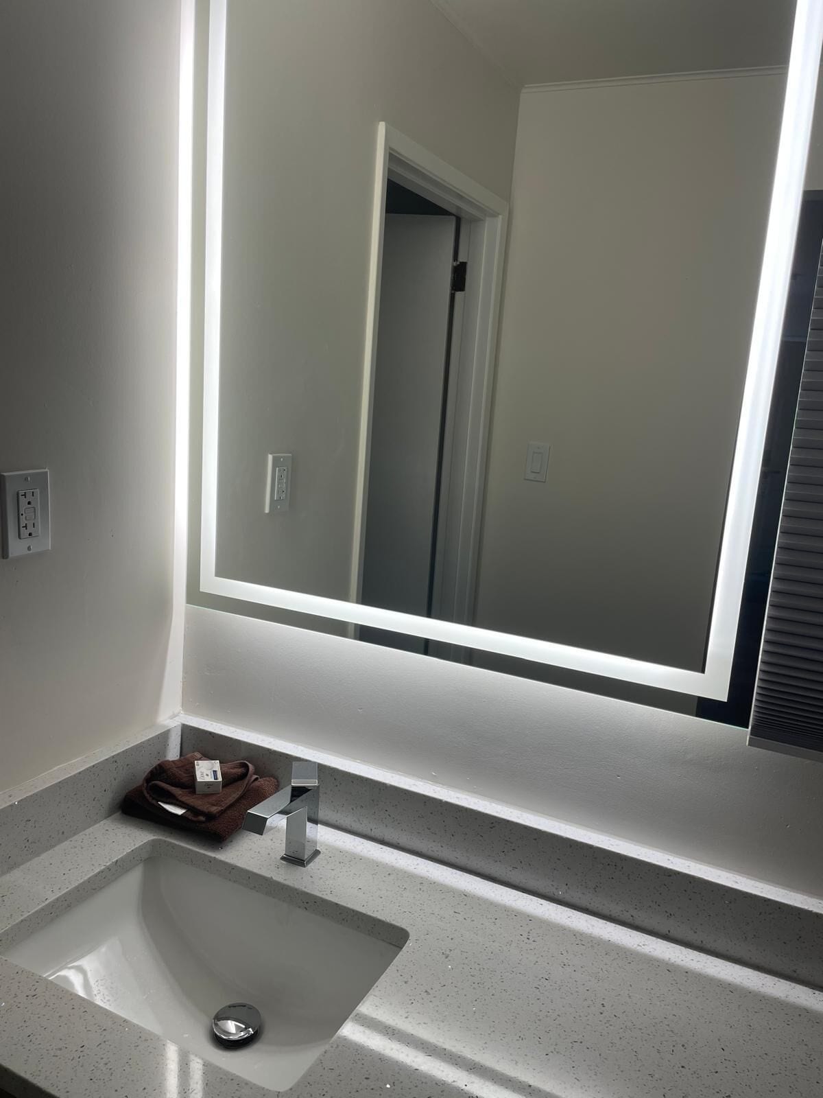 Un baño con un espejo grande, un lavabo y un perchero para toallas.