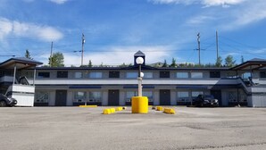 A motel with a central entrance, multiple rooms, and a parking area.