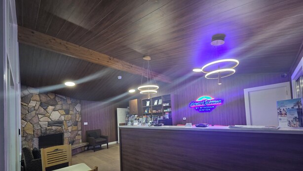 A reception area with a stone wall, wooden ceiling beams, and a neon sign.