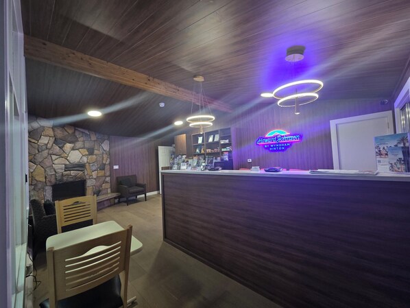 A reception area with a stone wall, wooden ceiling beams, and a neon sign.