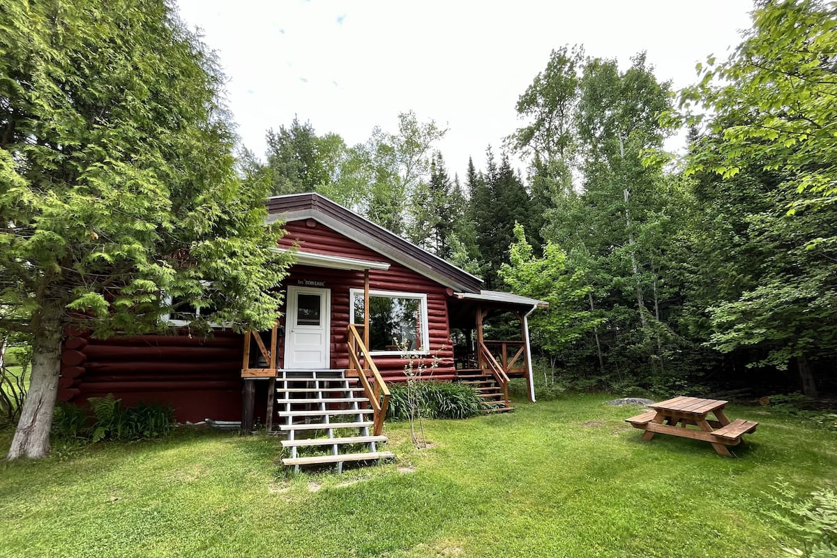 En hytte med veranda, trapper op til indgangen og et picnicbord i gården.