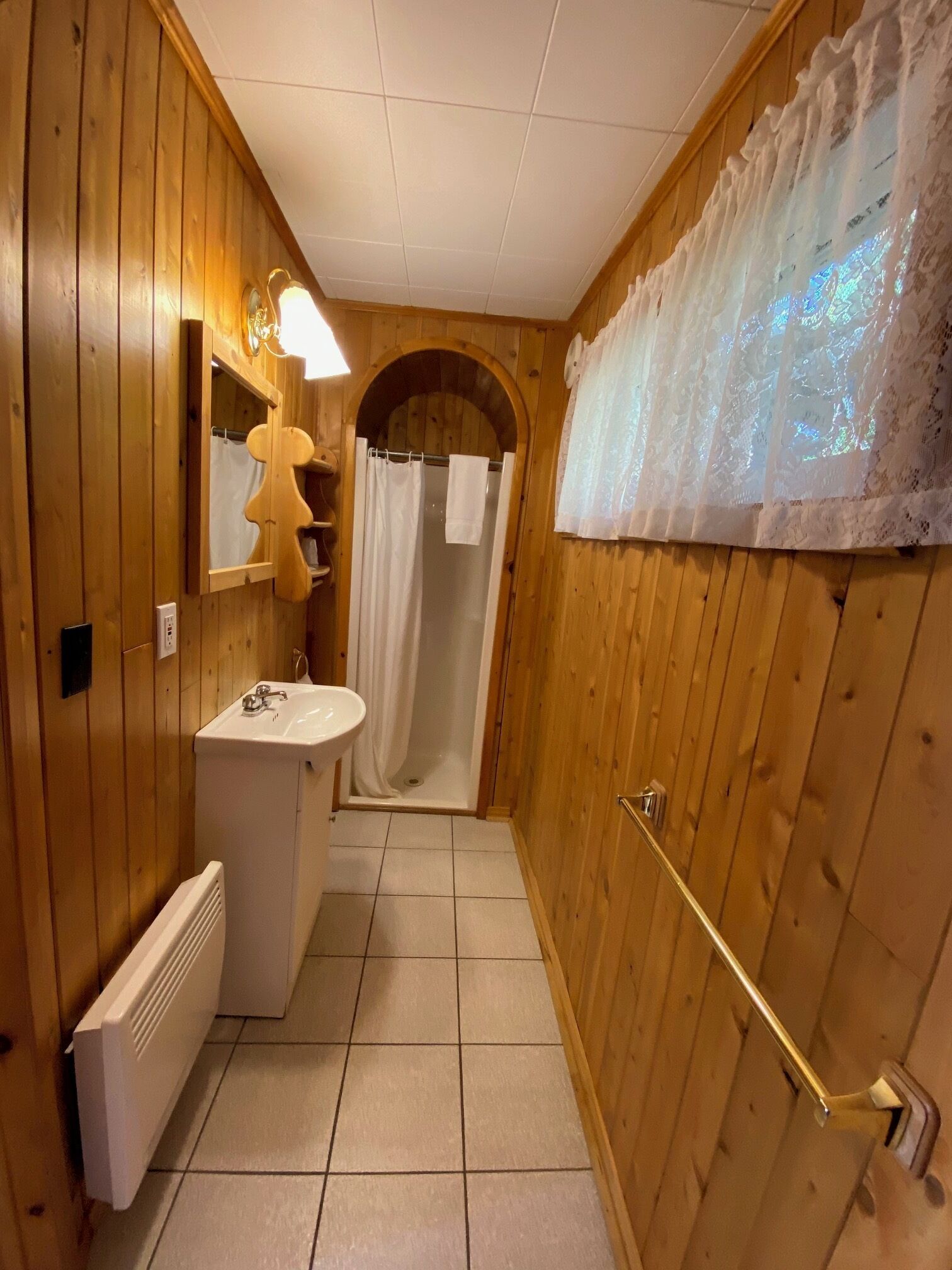 Ein schmales Badezimmer aus Holz mit Waschbecken, Spiegel und Dusche.