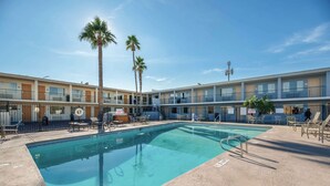 Un hotel con piscina, palmeras y mobiliario exterior.