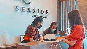 A reception desk at Seaside Jomtien Beach with two staff members attending to guests. - Seaside Jomtien Beach (Pattaya)