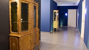 Un pasillo con un aparador dorado ornamentado y un espejo.