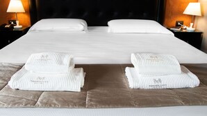 Una cama bien hecha con sábanas blancas y dos toallas sobre la cama.