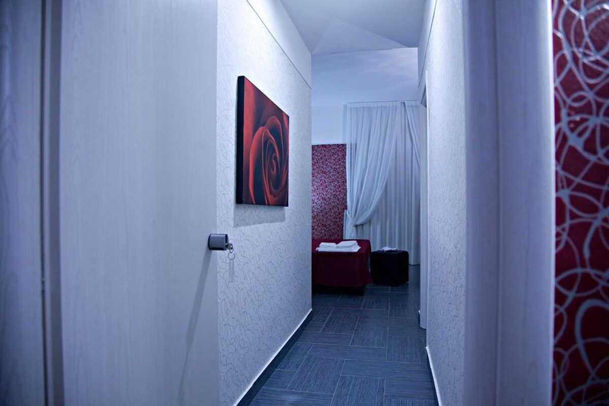 A narrow hallway with a bed and a red artwork on the wall.