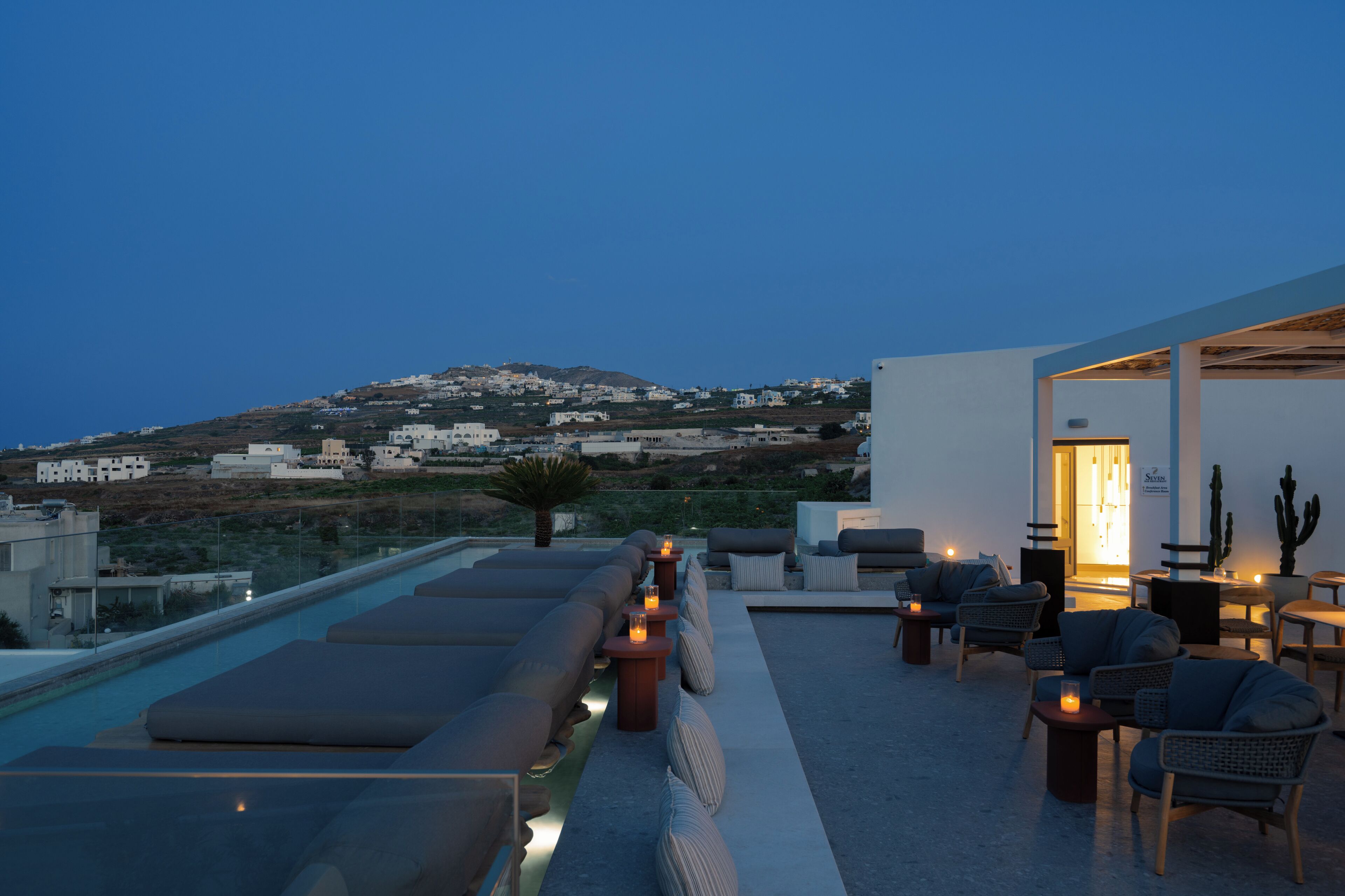 A rooftop terrace with a pool, seating area, and a view of a hillside.