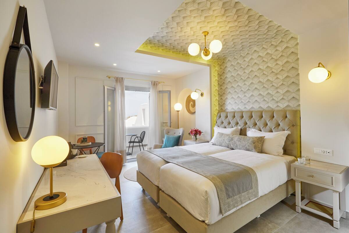 A modern bedroom with a large bed, a desk with a lamp, and a chair.