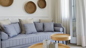 Una sala moderna con un sofá gris, dos mesas redondas de madera y decoración mural tejida.