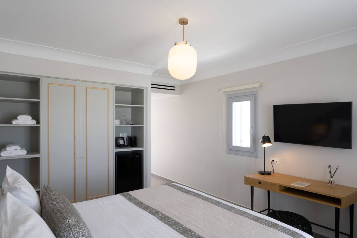 A hotel room with a bed, a desk, a TV, and a wardrobe.