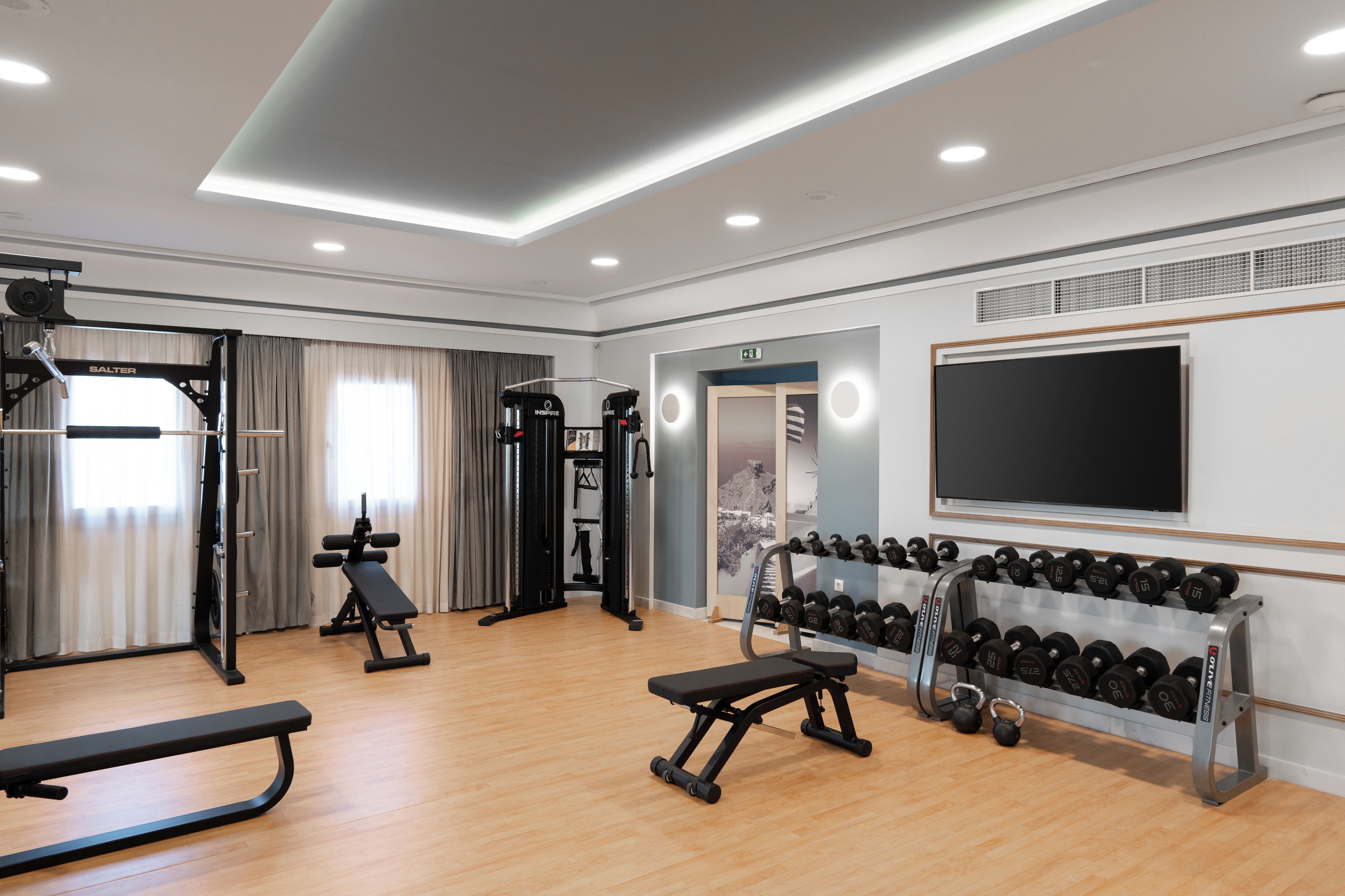 Een sportschool met diverse fitnessapparaten, waaronder een bank, gewichten en krachtapparaten.