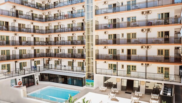 A multi-story hotel with balconies, a swimming pool, and outdoor seating areas. - Hotel Camposol (Benidorm)